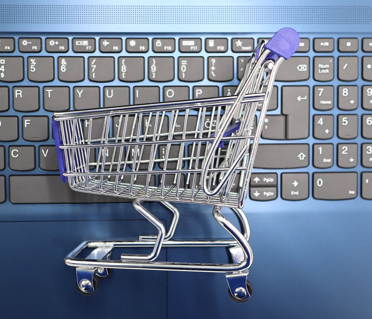 mobile-01 A miniature shopping cart placed on a laptop keyboard symbolizing online shopping and e-commerce.